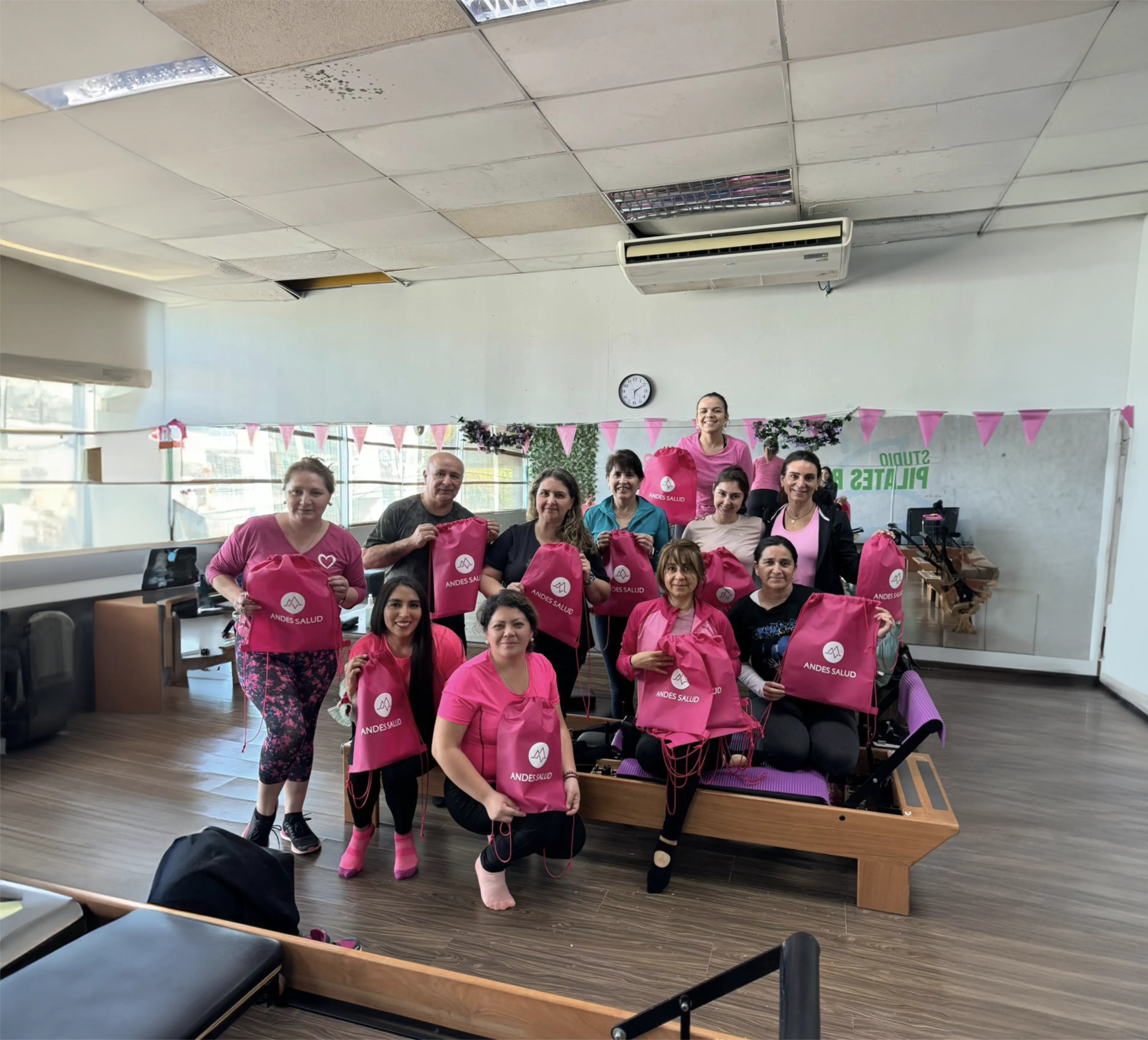 Grupo de mujeres con bolsas rosadas de Andes Salud tras una clase de pilates.