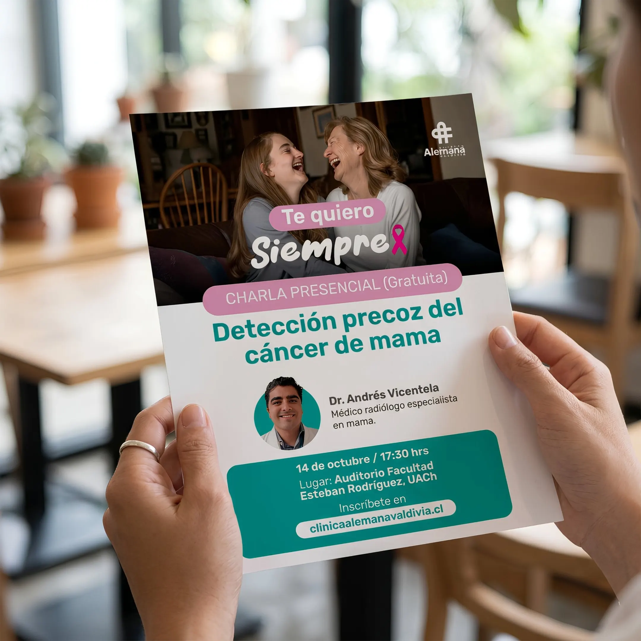 Flyer impreso de la charla "Detección precoz del cáncer de mama" de Clínica Alemana sostenido en mano.